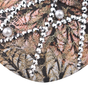 Detail of baseball cap featuring rhinestones and pearls on textured fabric surface