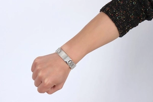 Macro shot of a silver stainless steel link bracelet worn on a wrist with white background