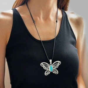 Detailed close-up of hollow butterfly pendant with turquoise stone on wax cord necklace