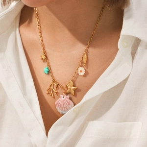 Detail of gold starfish and shell charms on a long link necklace worn by a model