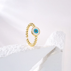 Detailed view of an 18K gold evil eye ring on white stone, featuring adjustable band design