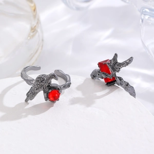 Macro shot of gothic dark thorn rings with crows and red rubies on white stones