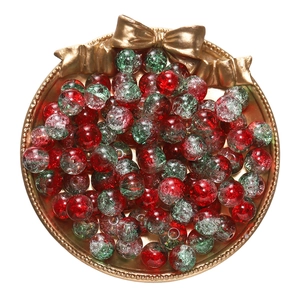 Macro shot of red and green crackle glass beads in a golden tray for DIY jewelry projects
