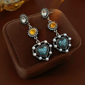 Detail of vintage heart earrings with blue rhinestones and pearls on brown velvet