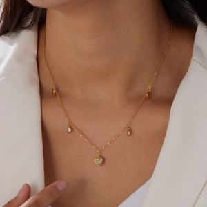 Close-up of heart and round crystal charms on a gold-plated stainless steel necklace