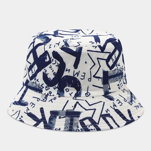 Detail of white bucket hat featuring navy graffiti patterns and reinforced stitching
