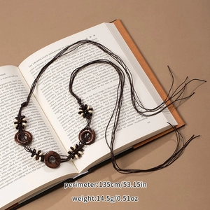 Detail of bohemian woven tassel belt with wooden rings and beads on book background