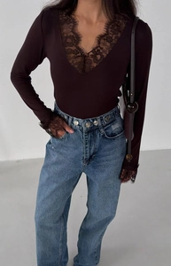 Detail of dark brown lace patchwork V-neck top paired with classic blue denim jeans