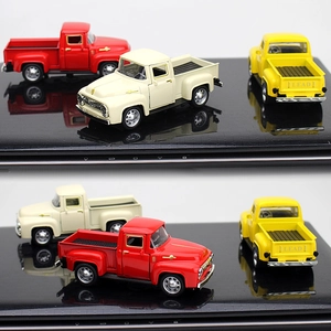 Three vintage alloy pickup truck models in red, beige and yellow on a reflective surface