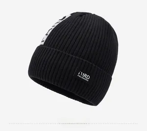 Close-up of the thick knit texture and brand label on a black winter beanie hat