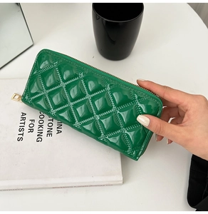 Macro shot of green quilted patent leather wallet with elegant gold zipper detail