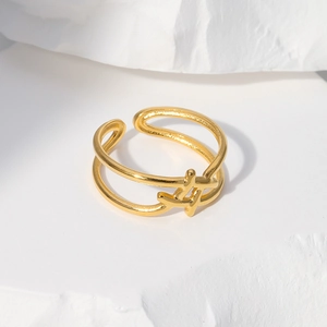 Detailed shot of a gold double-layer open ring featuring an abstract cross symbol