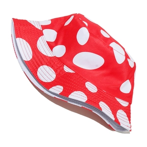 Détail d'un chapeau bob réversible rouge avec des pois blancs sur un fond blanc neutre