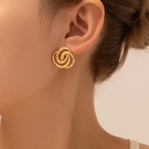Detail of gold knot earrings with textured hammered finish on a female model