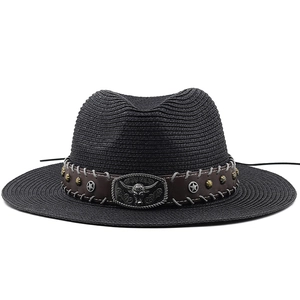 Detail of woven straw cowboy hat featuring brown leather band and bull head metal buckle