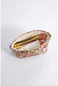 Overhead view of vintage floral jacquard cosmetic bag holding brushes and cream