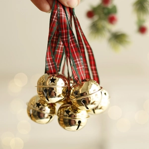 Golden Christmas bell ornaments with red plaid ribbons hanging on a festive tree