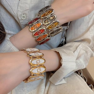 Detail of vintage oval enamel stretch bracelets with geometric logo in gold and silver finish