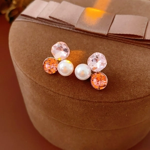 Detailed view of luxury triangle crystal and pearl earrings on brown velvet gift box
