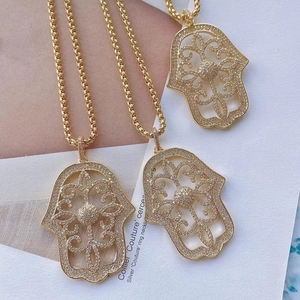 Close-up of three gold Hamsa Hand pendants with micro-pave zircon crystals for DIY jewelry