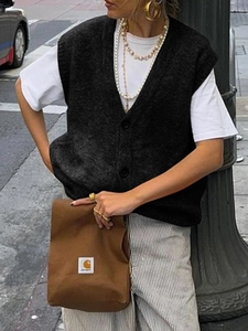 Gilet in maglia nera da donna con scollo a V e bottoni, mostrato in un look stile street