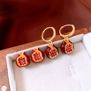Macro shot of 18K gold plated pomegranate earrings with red crystals in a jewelry box