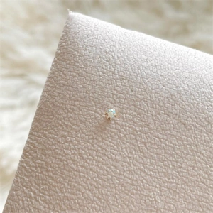 Macro shot of 925 sterling silver stud earring with AB crystal on cream leather
