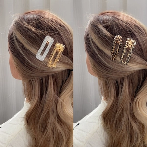 Square acrylic hair clips in leopard print and glitter gold finishes shown on wavy brown hair