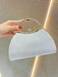 Close-up of silver pleated evening clutch with metal ring handle and rhinestone buckle