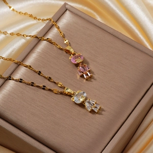 Close-up of gold bear pendant necklaces with pink and white zircon on silk fabric
