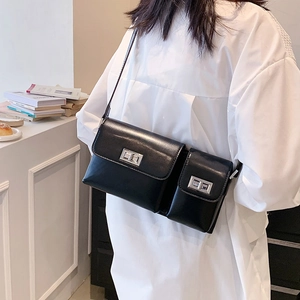 Detail of a black leather baguette bag with dual pockets and silver twist locks on a model