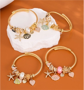 Detailed close-up of golden nautical bracelets with starfish, shell, and heart charms