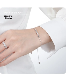 Détail d'un bracelet en argent ajustable avec perles et bague ondulée portée par un mannequin