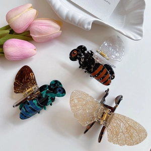 Trois pinces à cheveux en acétate en forme d'abeille en bleu, orange et crème