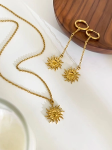 Detailed view of sunburst pendant jewelry set with necklace and earrings in 18K gold finish