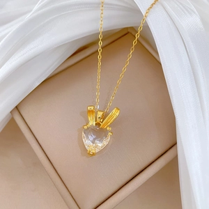 Golden heart pendant necklace with rabbit ears detail on soft beige jewelry box