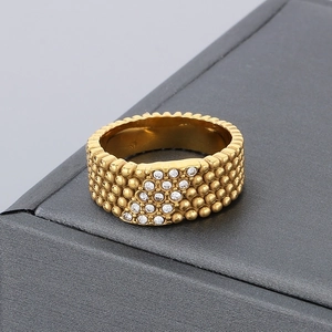 Macro shot of gold stainless steel ring with beaded texture and pavé set clear zircons