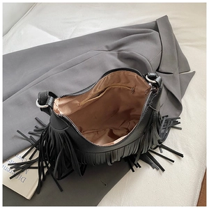 Detail view of black tassel shoulder bag with lychee grain texture and interior pocket