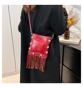 Detail of red leather crossbody bag featuring silver rivets and long tassel fringe decor