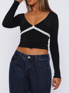 Détail du crop top noir à col en V avec dentelle blanche et manches longues