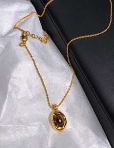 Close-up of gold plated necklace with oval brown tiger eye stone and twisted chain link
