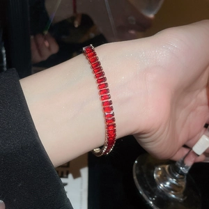 Macro detail of 18k gold tennis bracelet featuring rectangular red rubies on a model wrist
