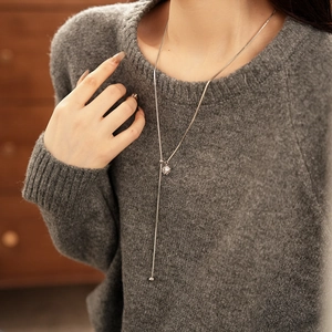 Close-up of long silver zircon tassel necklace with sliding buckle on grey knit sweater