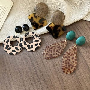 Close-up of geometric leopard print and wood drop earrings on burlap background