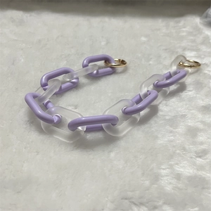 Close-up of lavender and frosted acrylic chain links with gold metal clasps on plush background