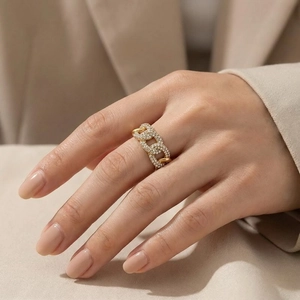 Detail of gold chain link ring with pavé diamond setting worn by a female model