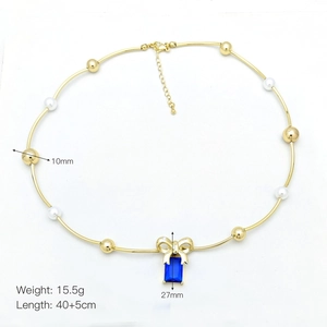Detail showing gold heart pearl necklace with blue gemstone pendant and bow accent