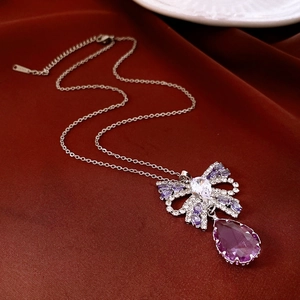Detail of vintage teardrop resin necklace with purple crystal bow on red velvet