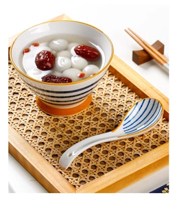 Close-up of a blue striped ceramic spoon resting on a bowl with red dates and soup