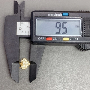 Digital caliper measuring the 9.5 mm width of a gold heart crystal pendant